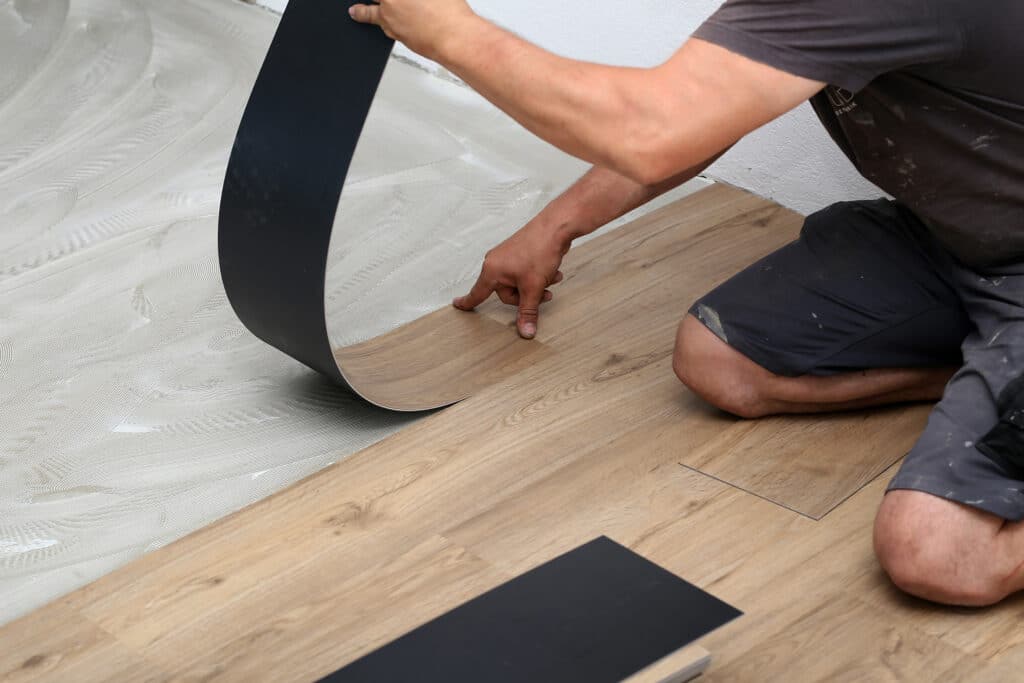 How to Clean Vinyl Flooring - worker laying down vinyl flooring