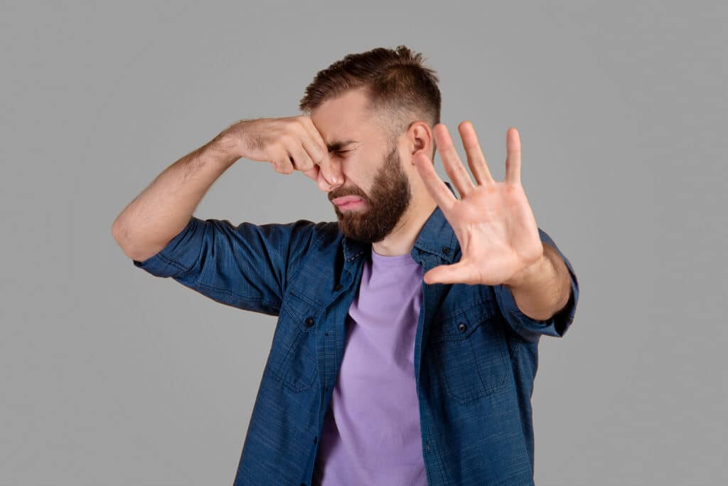 The Science of Odor Removal - man holding nose and palm towards us with disgust face